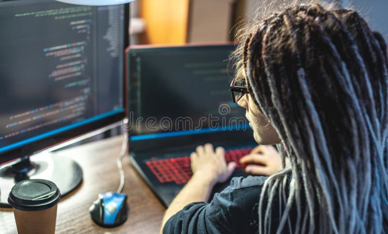 Modern young female programmer is writing program code on a laptop at home. Remote work in the IT profession royalty free stock photos