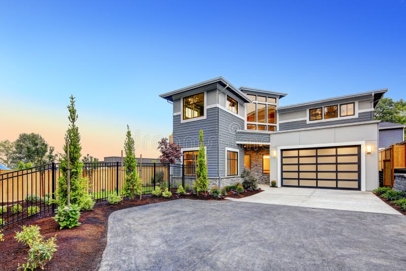 Excellent curb appeal of a Modern craftsman style home accented by landscaping, gray siding, large windows and Frosted Glass Garage Door. Northwest, USA. Excellent curb appeal of a Modern craftsman style home accented by landscaping, gray siding, large windows and Frosted Glass Garage Door. Northwest, USA