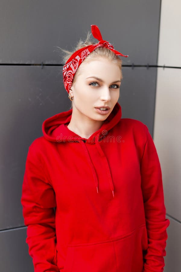 Moderne nette junge Frau mit natürlichem Make-up mit dem blonden Haar in einem amerikanischen roten Bandana in einer modischen mi stockfotografie Moderne nette junge Frau mit natürlichem Make-up mit dem blonden Haar in einem amerikanischen roten Bandana in einer modischen mi stockfotografie
