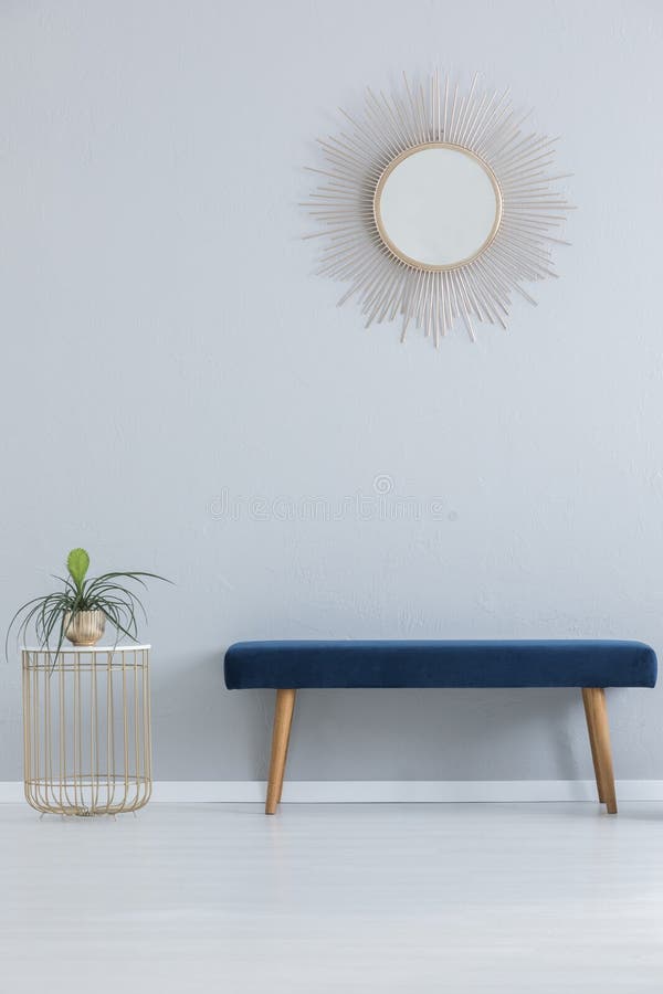 Moderne spiegel boven blauwe sofa en modieuze lijst met installatie in gouden pot, echte foto stock fotografie Moderne spiegel boven blauwe sofa en modieuze lijst met installatie in gouden pot, echte foto stock fotografie