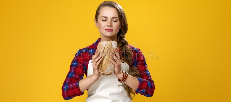 Moderne vrouwenlandbouwer die op gele achtergrond van vers brood genieten stock foto Moderne vrouwenlandbouwer die op gele achtergrond van vers brood genieten stock foto