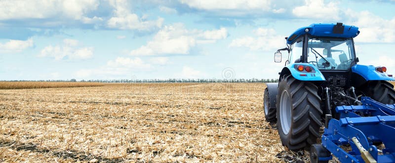 Tractor working on the farm, a modern agricultural transport, cultivation of fertile land, tractor on cloudy sky background, agricultural machine. Tractor working on the farm, a modern agricultural transport, cultivation of fertile land, tractor on cloudy sky background, agricultural machine