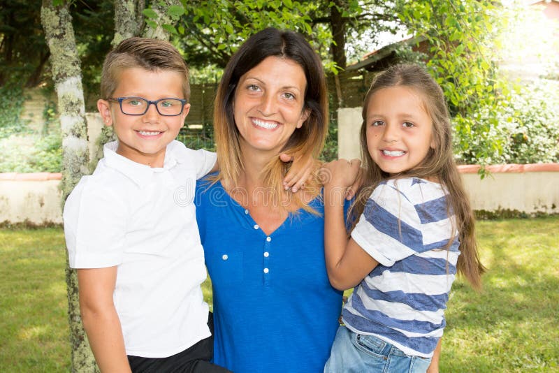 Modernes Familienallein erziehende mutter-Elternteil mit zwei Kindern Tochter und Sohn in den Armen im Haupthaus arbeiten im Gart stockfotografie Modernes Familienallein erziehende mutter-Elternteil mit zwei Kindern Tochter und Sohn in den Armen im Haupthaus arbeiten im Gart stockfotografie