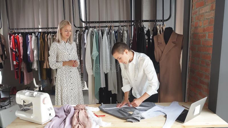 Moderni designer di abbigliamento e potenziale cliente sul posto di lavoro discutono di design di futuri vestiti