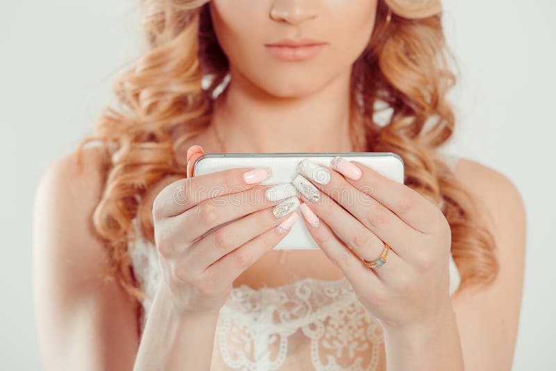 Trendy with phone. Nail Polish. Art Manicure. Modern style pink white Nail Polish. Beauty hands holding mobile cellphone. Stylish pastel Color classic bride Nails design  white background wall. Trendy with phone. Nail Polish. Art Manicure. Modern style pink white Nail Polish. Beauty hands holding mobile cellphone. Stylish pastel Color classic bride Nails design  white background wall