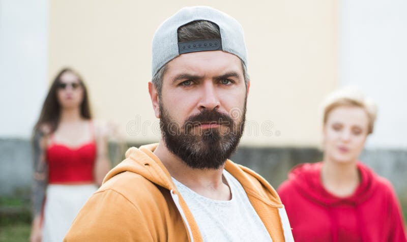 Moderno fresco Homem farpado no tamp?o do moderno da forma exterior Homem brutal com barba e o bigode longos Rua do moderno foto de stock Moderno fresco Homem farpado no tamp?o do moderno da forma exterior Homem brutal com barba e o bigode longos Rua do moderno foto de stock