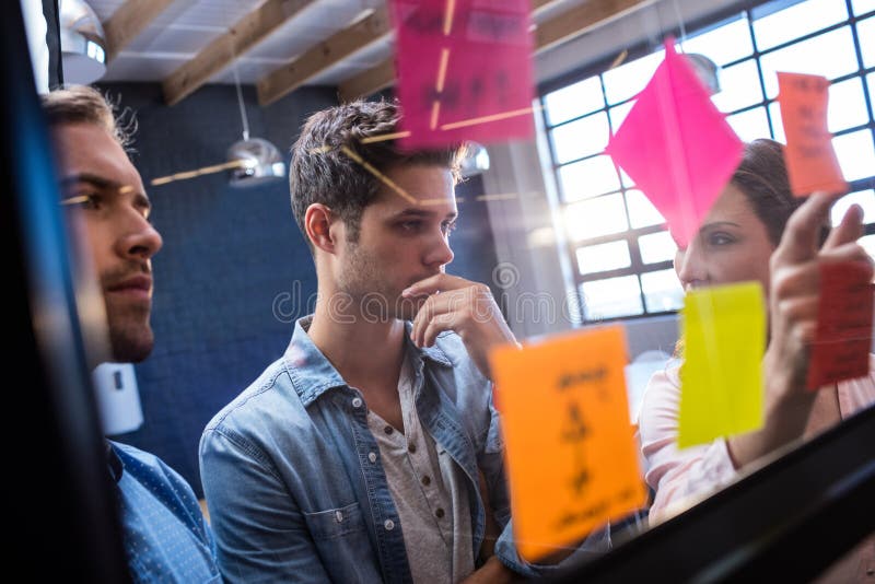 Modernos que leem um post-it em uma janela imagem de stock royalty free Modernos que leem um post-it em uma janela imagem de stock royalty free
