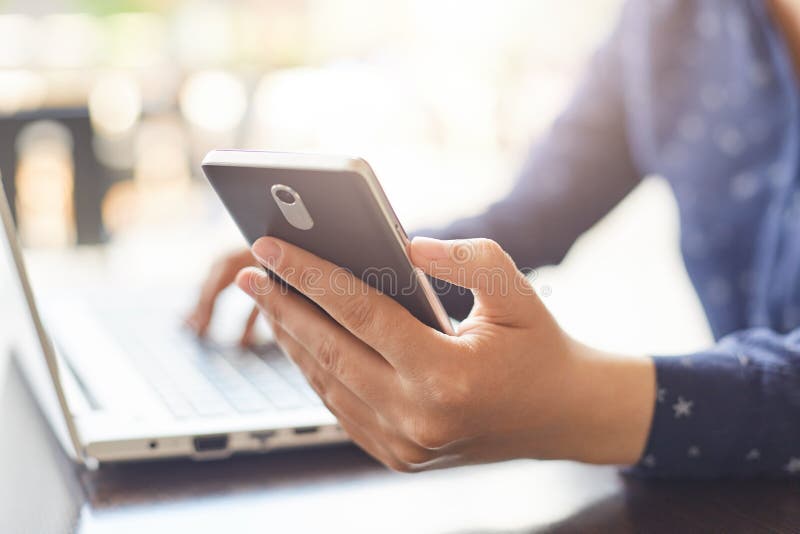 Modernt teknologi- och livsstilbegrepp En närbild av kvinna` s räcker den hållande smartphonen och maskinskrivning något på henne royaltyfria bilder