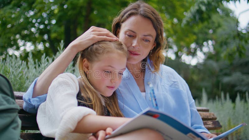 Modersdotter gör läxor tillsammans i parken. Skriv anteckningsbok lager videofilmer