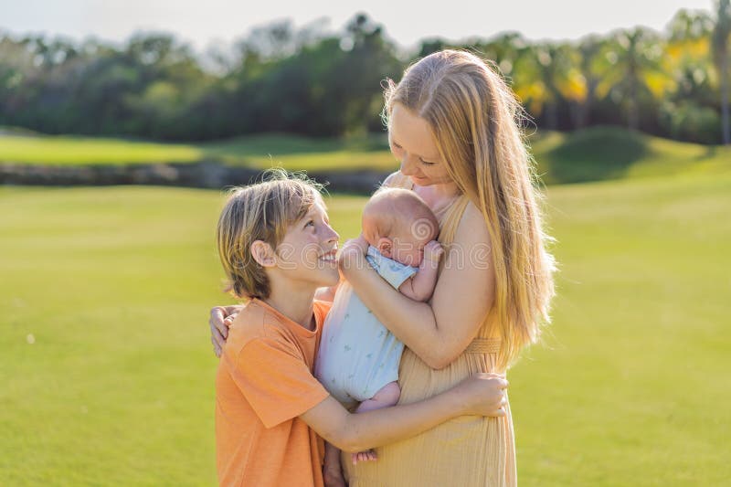 Moderäldre son och nyfödda barn på en ängsmark i parken. Familjeutgifter av hög kvalitet tillsammans i naturen. Parenthood royaltyfria foton