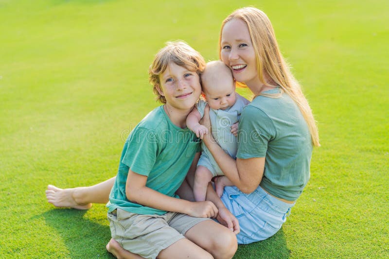 Moderäldre son och nyfödda barn på en ängsmark i parken. Familjeutgifter av hög kvalitet tillsammans i naturen. Parenthood arkivfoton