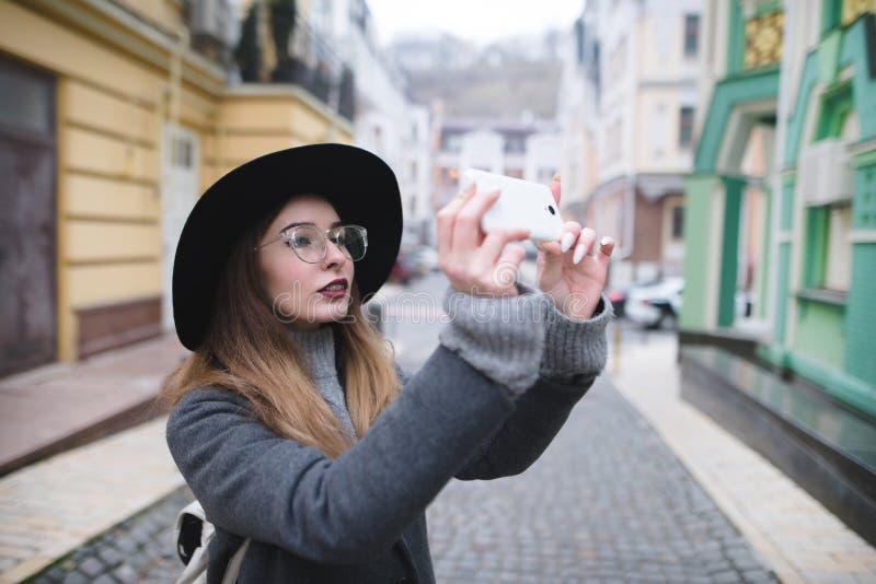 Modieus meisje die een straatfoto op de telefoon fotograferen Een toeristenmeisje maakt een foto van architectuur op een smartpho stock foto's Modieus meisje die een straatfoto op de telefoon fotograferen Een toeristenmeisje maakt een foto van architectuur op een smartpho stock foto's