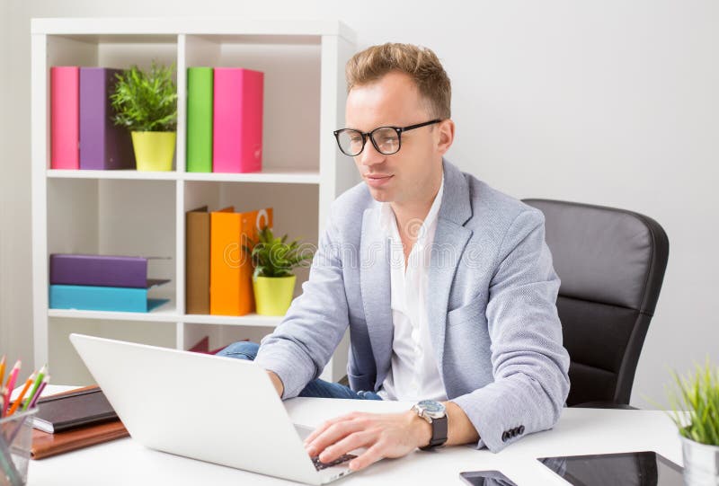 Modieuze jonge mens die met computer in bureau werken royalty-vrije stock fotografie Modieuze jonge mens die met computer in bureau werken royalty-vrije stock fotografie
