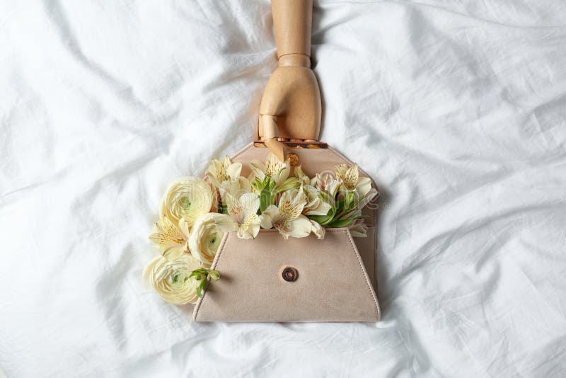 Modieuze koppeling met de lentebloemen en houten ledenpophand op verfrommeld blad stock fotografie Modieuze koppeling met de lentebloemen en houten ledenpophand op verfrommeld blad stock fotografie