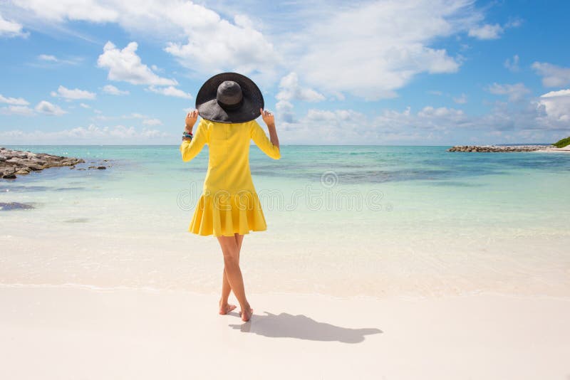 Modieuze vrouw met zwarte de zomerhoed en gele kleding op het strand royalty-vrije stock afbeeldingen Modieuze vrouw met zwarte de zomerhoed en gele kleding op het strand royalty-vrije stock afbeeldingen