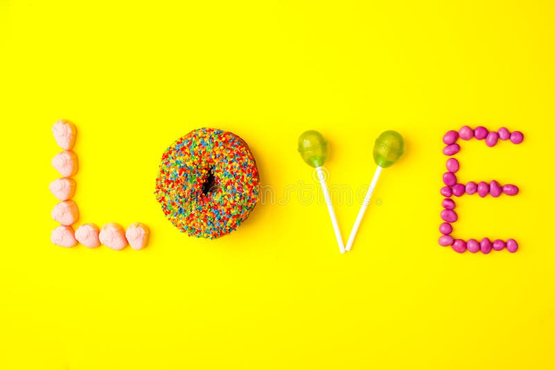 Modische Ebenenlagebeschriftung Aufschriftliebe durch Bonbons jn Gelbhintergrund stockbilder Modische Ebenenlagebeschriftung Aufschriftliebe durch Bonbons jn Gelbhintergrund stockbilder
