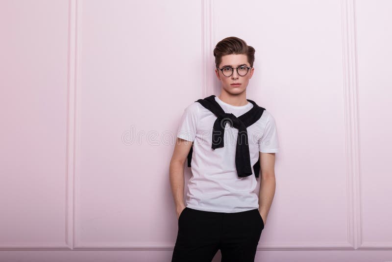 Modny, atrakcyjny model młodzieńczy w okularach vintage z fryzurą w modnej białej koszulce w czarnych dżinsach z nosem fotografia royalty free