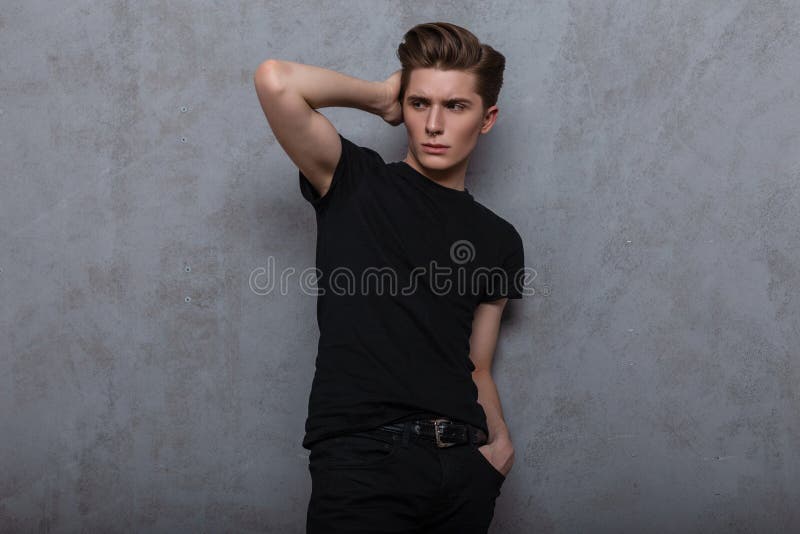 Modny, atrakcyjny model młodzieńczy ze stylową fryzurą w modnej czarnej koszuli w vintage jeans z przekłuciem nosa zdjęcie stock