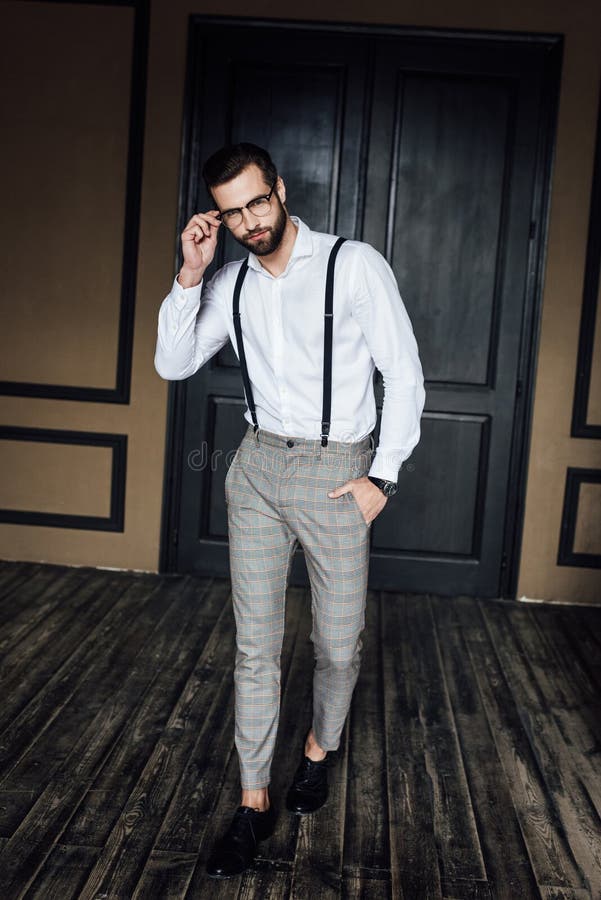 fashionable elegant man posing in white shirt and suspenders in loft interior. fashionable elegant man posing in white shirt and suspenders in loft interior