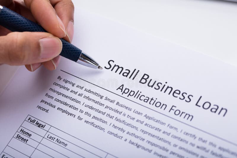 Modulo di domanda di prestito di Filling Small Business della persona di affari fotografie stock Modulo di domanda di prestito di Filling Small Business della persona di affari fotografie stock