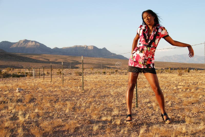 African American model posing against a wire fence in the desert in warm afternoon sunlight. African American model posing against a wire fence in the desert in warm afternoon sunlight.