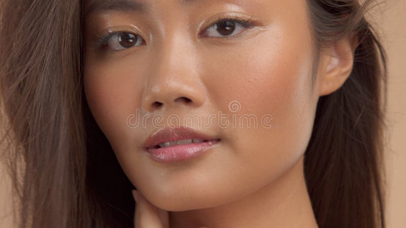 Modèle asiatique thaïlandais avec le maquillage naturel sur le fond beige
