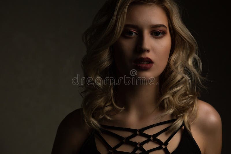 Modèle blond de charme avec la peau rougeoyante et les épaules nues posant avec la lumière de contraste L'espace vide images libres de droits Modèle blond de charme avec la peau rougeoyante et les épaules nues posant avec la lumière de contraste L'espace vide images libres de droits