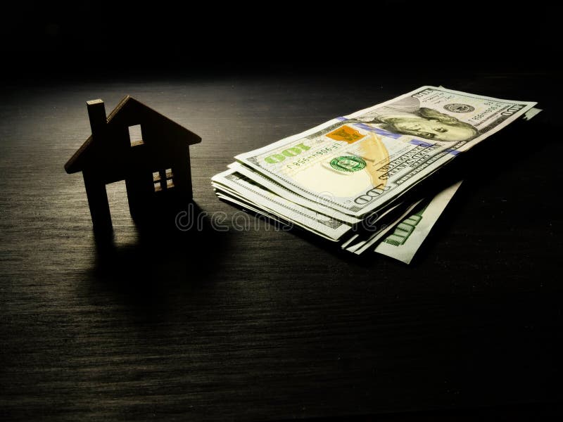 Modèle de maison et d'argent dans l'obscurité Hypothèque ou dollars pour le loyer image stock Modèle de maison et d'argent dans l'obscurité Hypothèque ou dollars pour le loyer image stock