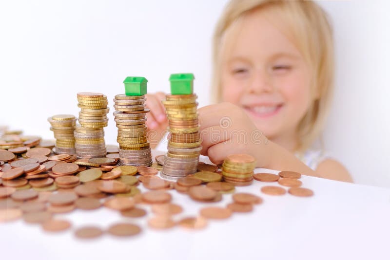 House model on stacks euro currency coins, small child, blonde girl 3 years old playing with cash, pocket money, concept home mortgage, home insurance, financial literacy of children, personal savings. House model on stacks euro currency coins, small child, blonde girl 3 years old playing with cash, pocket money, concept home mortgage, home insurance, financial literacy of children, personal savings