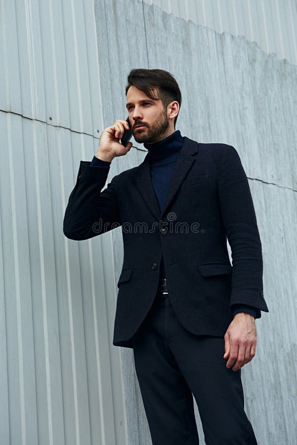 Mod?le masculin beau d'affaires de style de barbe de mode fonctionnant et invitant le t?l?phone portable dans l'habillement de st image libre de droits Mod?le masculin beau d'affaires de style de barbe de mode fonctionnant et invitant le t?l?phone portable dans l'habillement de st image libre de droits