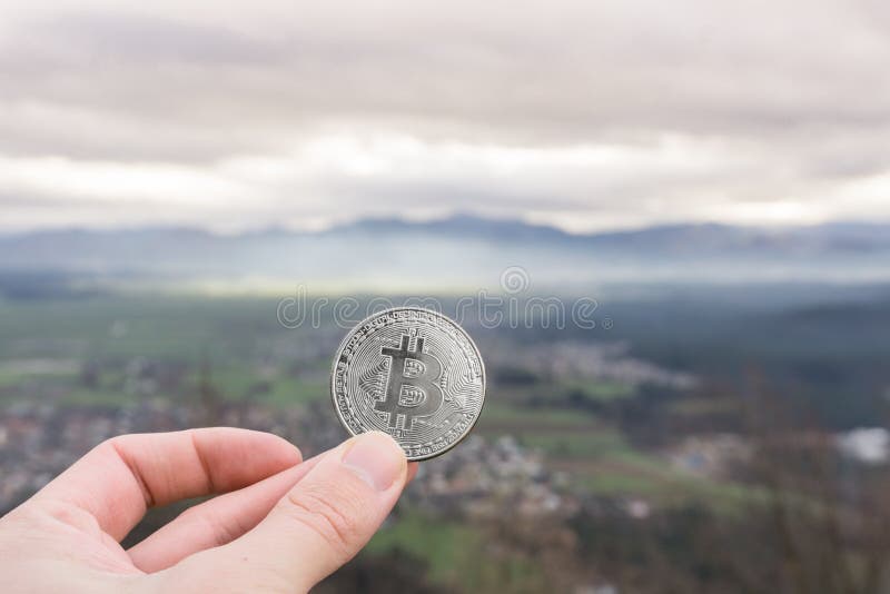 Moeda de prata de Bitcoin, bitcoin da posse da mão acima da cidade imagem de stock Moeda de prata de Bitcoin, bitcoin da posse da mão acima da cidade imagem de stock