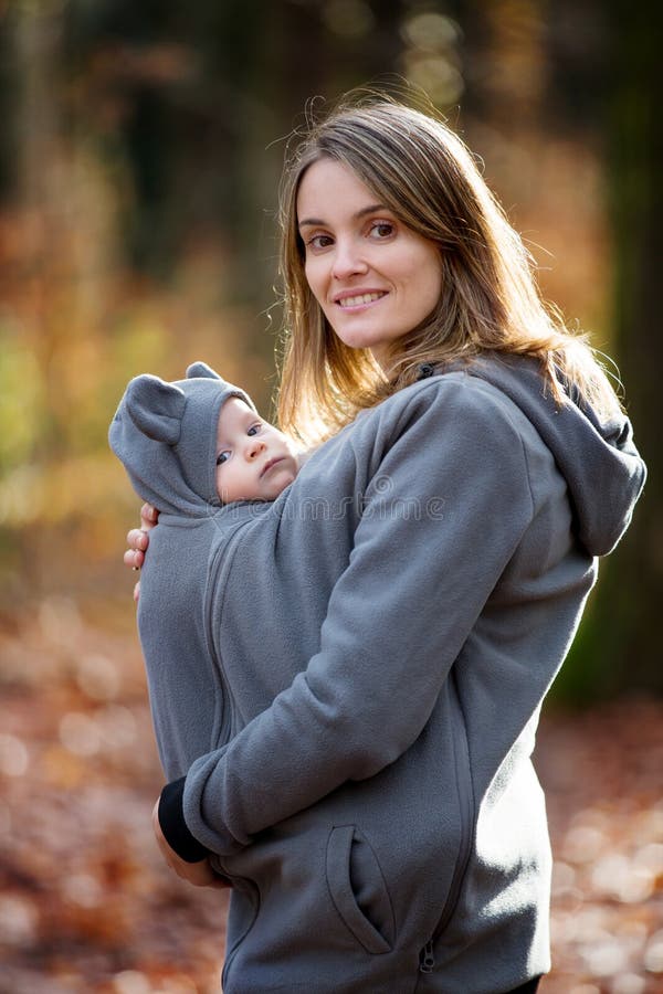 Moeder, die haar babyjongen in een slinger vervoeren, in openlucht royalty-vrije stock afbeeldingen Moeder, die haar babyjongen in een slinger vervoeren, in openlucht royalty-vrije stock afbeeldingen