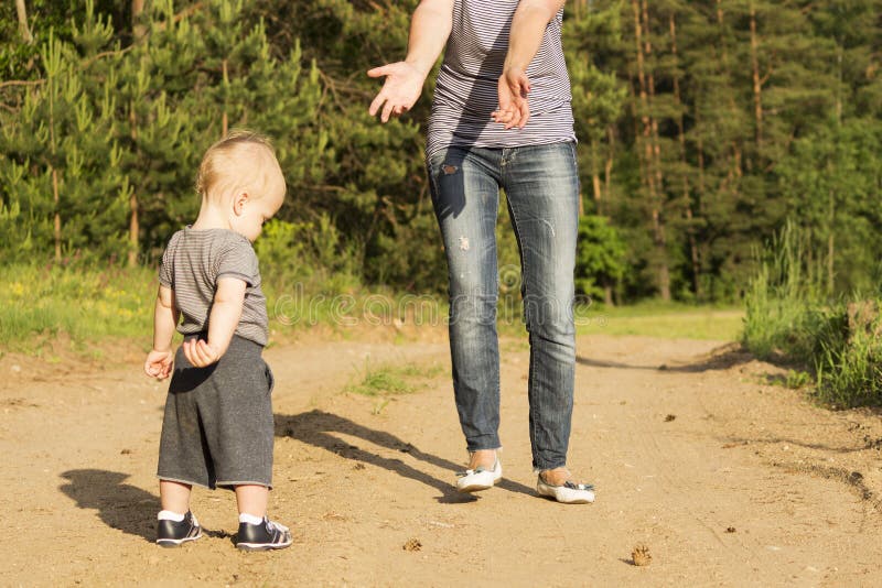 Moeder die haar de jongenszoon van de één jaarbaby voor het lopen onderwijzen Schuwe peuter die eerste stappen proberen te maken royalty-vrije stock afbeelding Moeder die haar de jongenszoon van de één jaarbaby voor het lopen onderwijzen Schuwe peuter die eerste stappen proberen te maken royalty-vrije stock afbeelding