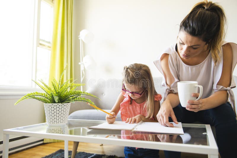 Moeder die haar dochter helpen tijdens haar thuiswerk in de woonkamer stock foto Moeder die haar dochter helpen tijdens haar thuiswerk in de woonkamer stock foto
