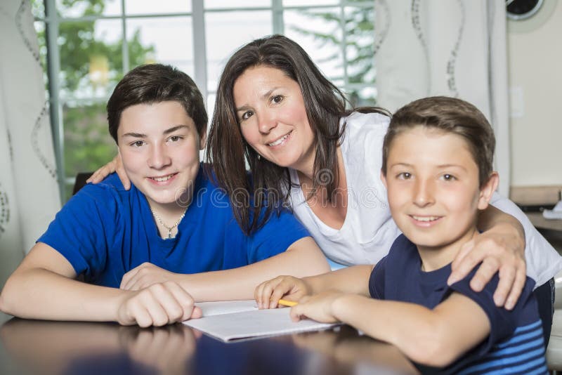 Moeder die Zoon met Thuiswerk helpen bij Lijst stock foto's Moeder die Zoon met Thuiswerk helpen bij Lijst stock foto's