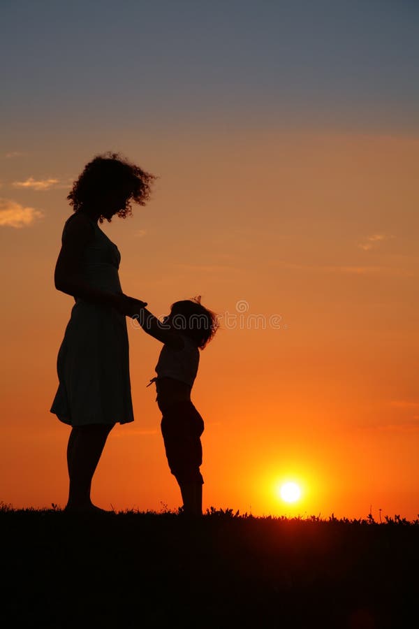 Moeder en dochter op zonsondergangsilhouet royalty-vrije stock afbeelding Moeder en dochter op zonsondergangsilhouet royalty-vrije stock afbeelding