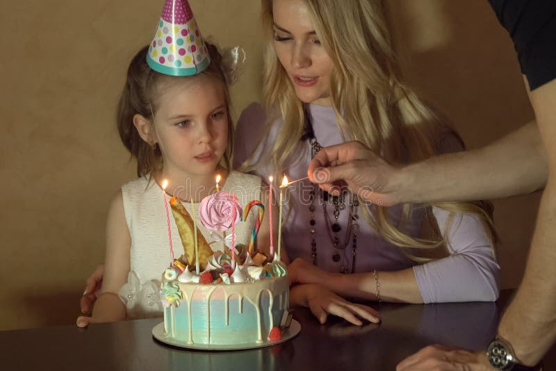 Moeder en dochter tellende kaarsen op een verjaardagscake meisje in een feestelijke hoed bij een children& x27; s partij stock foto Moeder en dochter tellende kaarsen op een verjaardagscake meisje in een feestelijke hoed bij een children& x27; s partij stock foto