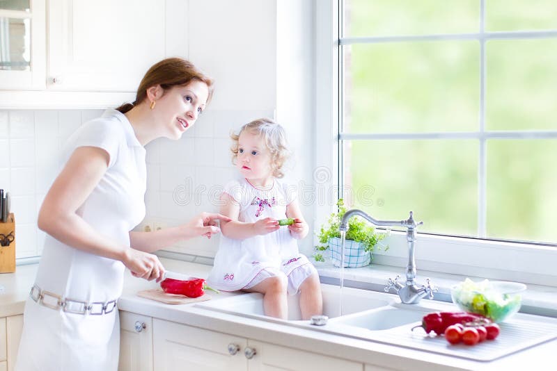 Moeder en haar de wasgroenten van de peuterdochter stock fotografie Moeder en haar de wasgroenten van de peuterdochter stock fotografie