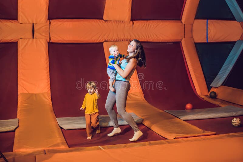 Moeder en haar zoon die op een trampoline in geschiktheidspark springen en exersice binnen doen stock fotografie Moeder en haar zoon die op een trampoline in geschiktheidspark springen en exersice binnen doen stock fotografie
