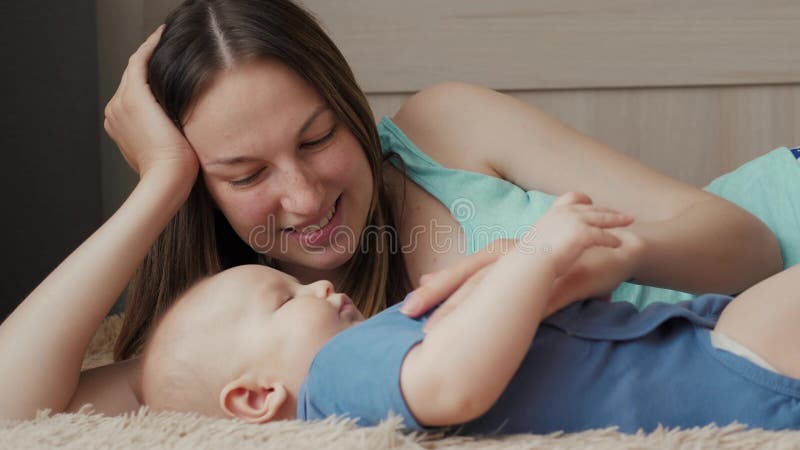 Moeder en kind op een wit bed Mamma en babyjongen in luier het spelen in zonnige slaapkamer Ouder en weinig jong geitje het ontsp