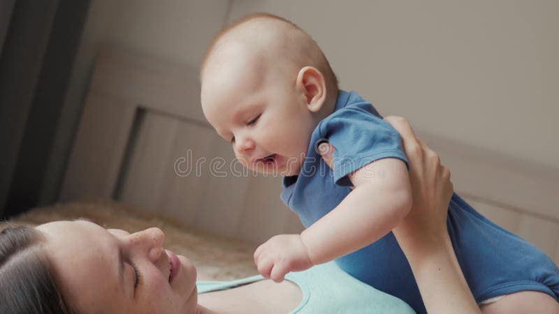 Moeder en kind op een wit bed Mamma en babyjongen in luier het spelen in zonnige slaapkamer Ouder en weinig jong geitje het ontsp