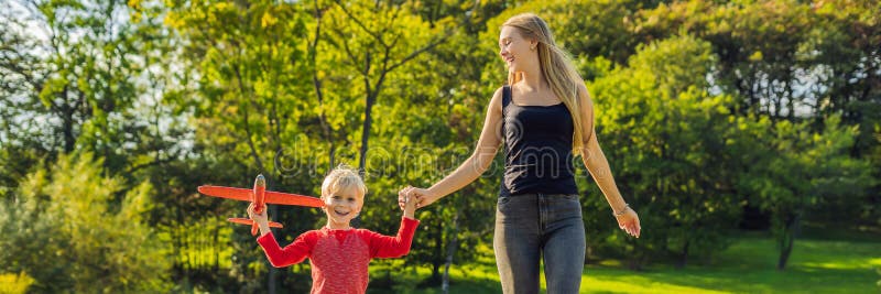Moeder en zoons het spelen met een groot modelstuk speelgoed vliegtuig in de parkbanner, LANG FORMAAT stock afbeeldingen Moeder en zoons het spelen met een groot modelstuk speelgoed vliegtuig in de parkbanner, LANG FORMAAT stock afbeeldingen