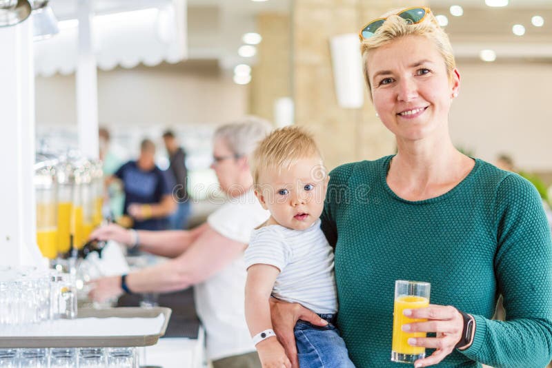 Moeder met babyjongen die van jus d'orange in al inclusief restaurant genieten royalty-vrije stock afbeelding Moeder met babyjongen die van jus d'orange in al inclusief restaurant genieten royalty-vrije stock afbeelding