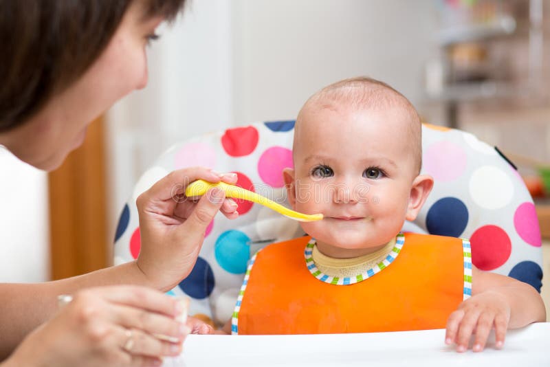 Moeder voedende baby op keuken stock afbeeldingen Moeder voedende baby op keuken stock afbeeldingen