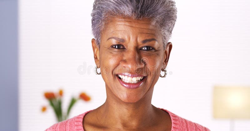 Mogen afrikansk kvinna som ler på kameran