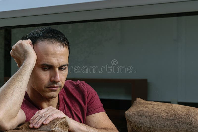 44-year-old man in a photo session on the brown sofa, doing various poses, joy, serious, sadness, with smartphone in hand and staring at the camera. 44-year-old man in a photo session on the brown sofa, doing various poses, joy, serious, sadness, with smartphone in hand and staring at the camera.