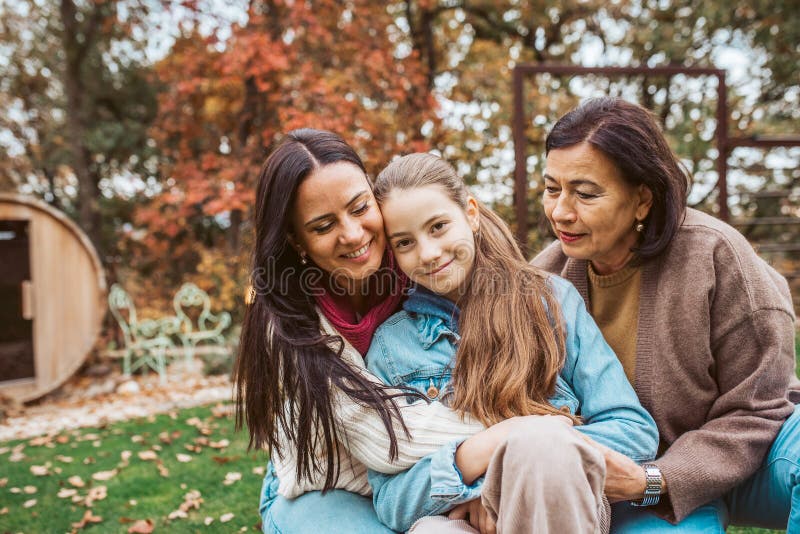 Mogen dottermor och barnmorska som sitter i trädgården. Mödrar dag och familj med flera generationer arkivfoto