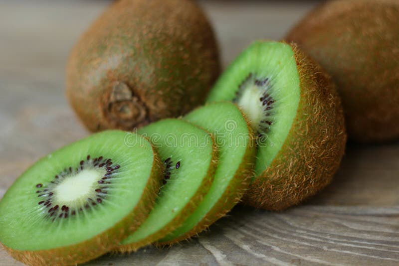 Mogen kiwi, saftigt, snitt in i stycken som isoleras på träbrun bakgrund arkivbilder Mogen kiwi, saftigt, snitt in i stycken som isoleras på träbrun bakgrund arkivbilder