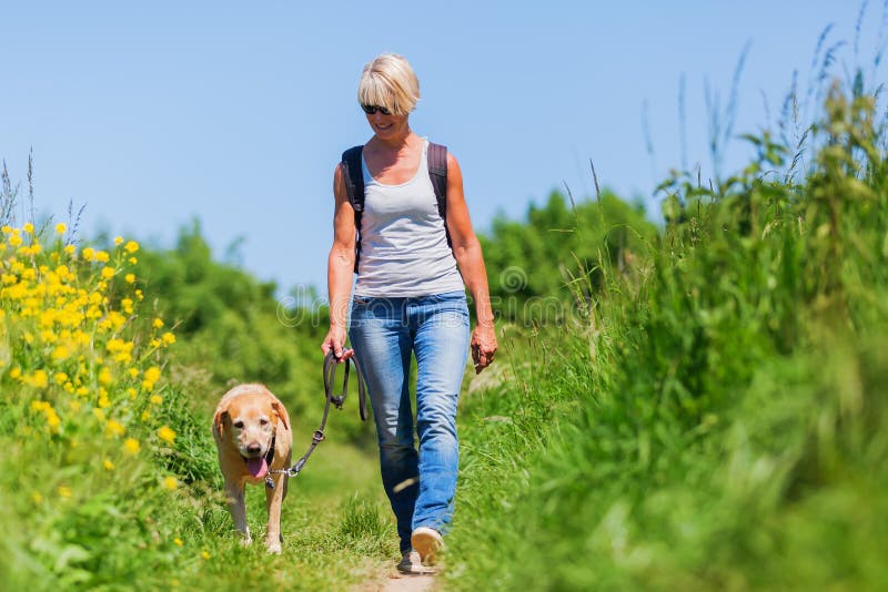 Mogen kvinna med hunden som tar att fotvandra i landet royaltyfri fotografi Mogen kvinna med hunden som tar att fotvandra i landet royaltyfri fotografi
