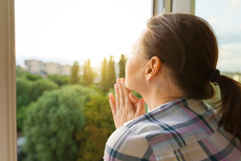 Mogen kvinna som ut ser fönstret, närbildsikt från baksidan arkivfoto